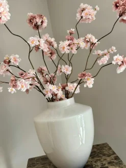 Beige vaas met roze zijden bloesemtakken
