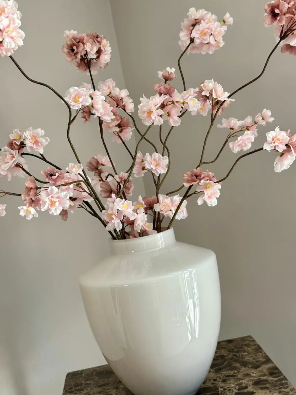 Beige vaas met roze zijden bloesemtakken